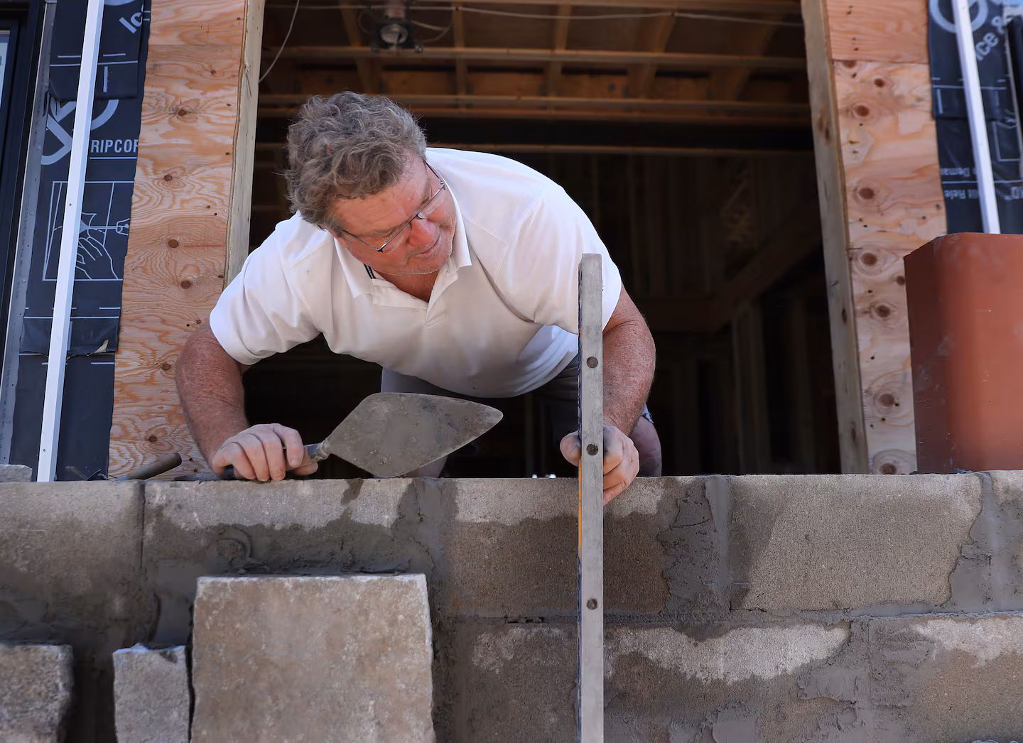Marty Nally setting stone with a trowel on a job site