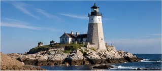 White lighthouse and keeper's house on a rocky island (illustrative photograph)